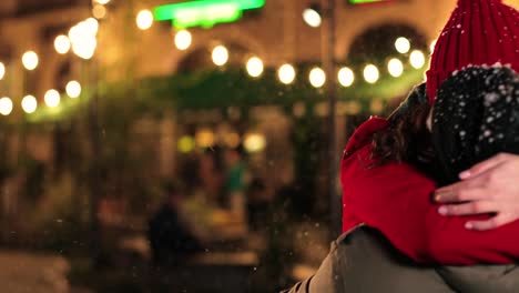 close-up view of joyful multiethnic couple hugging and smiling while it¬¥s snowing on the street in christmas