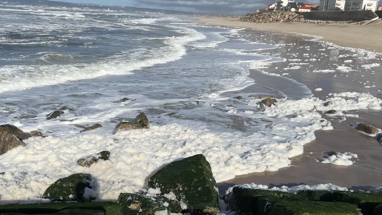 Onde che si infrangono sulla riva con forza durante un pomeriggio di tempesta.