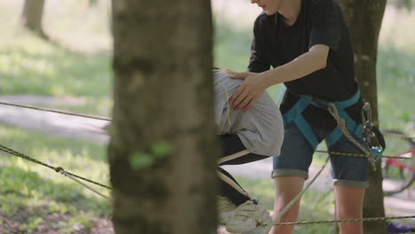 active child fearlessly climbs the ropes between the trees. girl in an adventure park are pass obstacles on the rope road. children camp summer camp