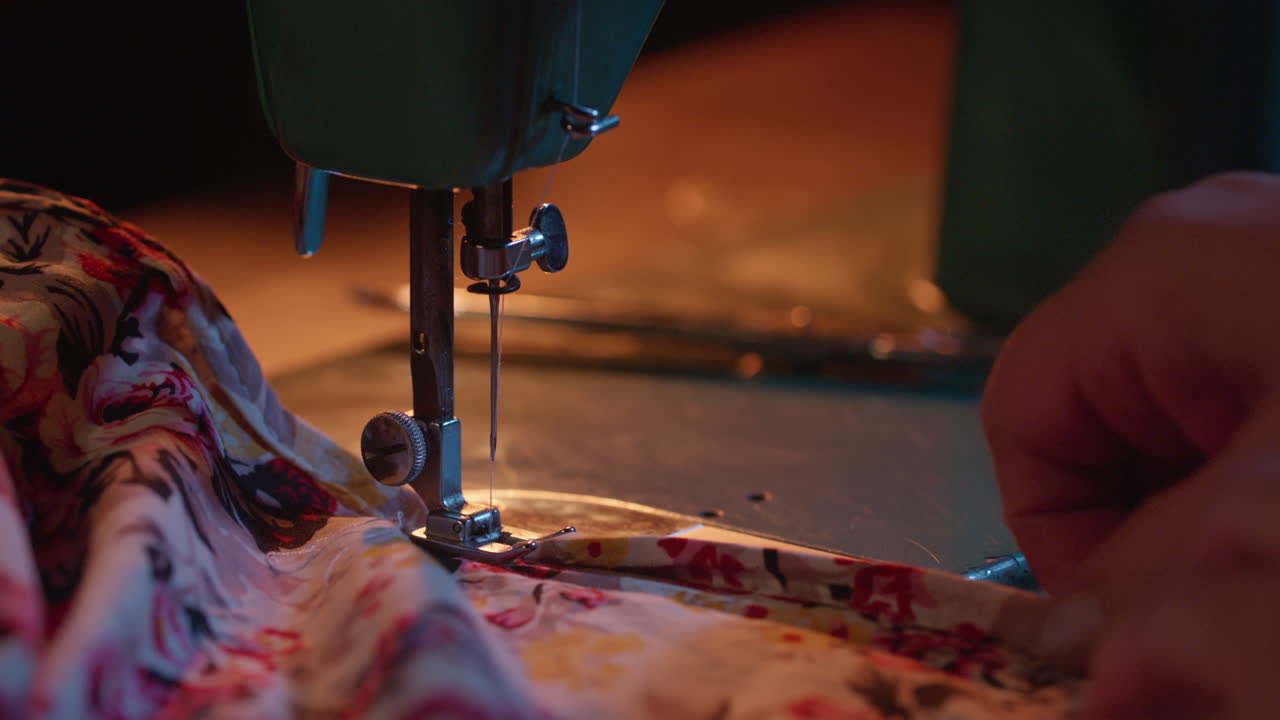Close-up of Hands Guiding Floral Fabric Through a Sewing Machine