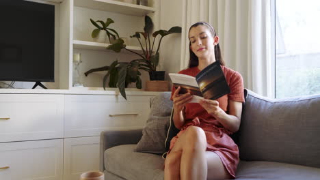 woman relaxing on sofa reading book at home, enjoying peaceful afternoon