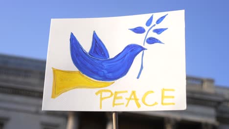 London-stands-with-Ukraine,-blue-and-yellow-dove,-protester-sign-of-peace-in-Trafalgar-Square-in-London-during-protest-against-war-with-Russia