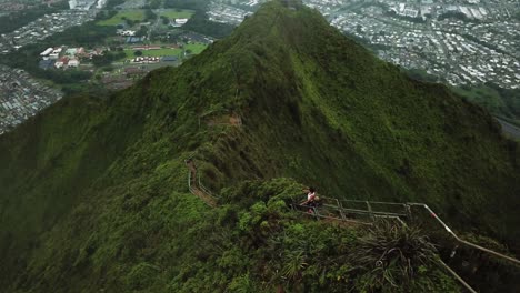 aerial view of hikers on the haiku stairs trail, or stairway to heaven. kaneohe city, oahu can be seen at the bottom of the mountain.