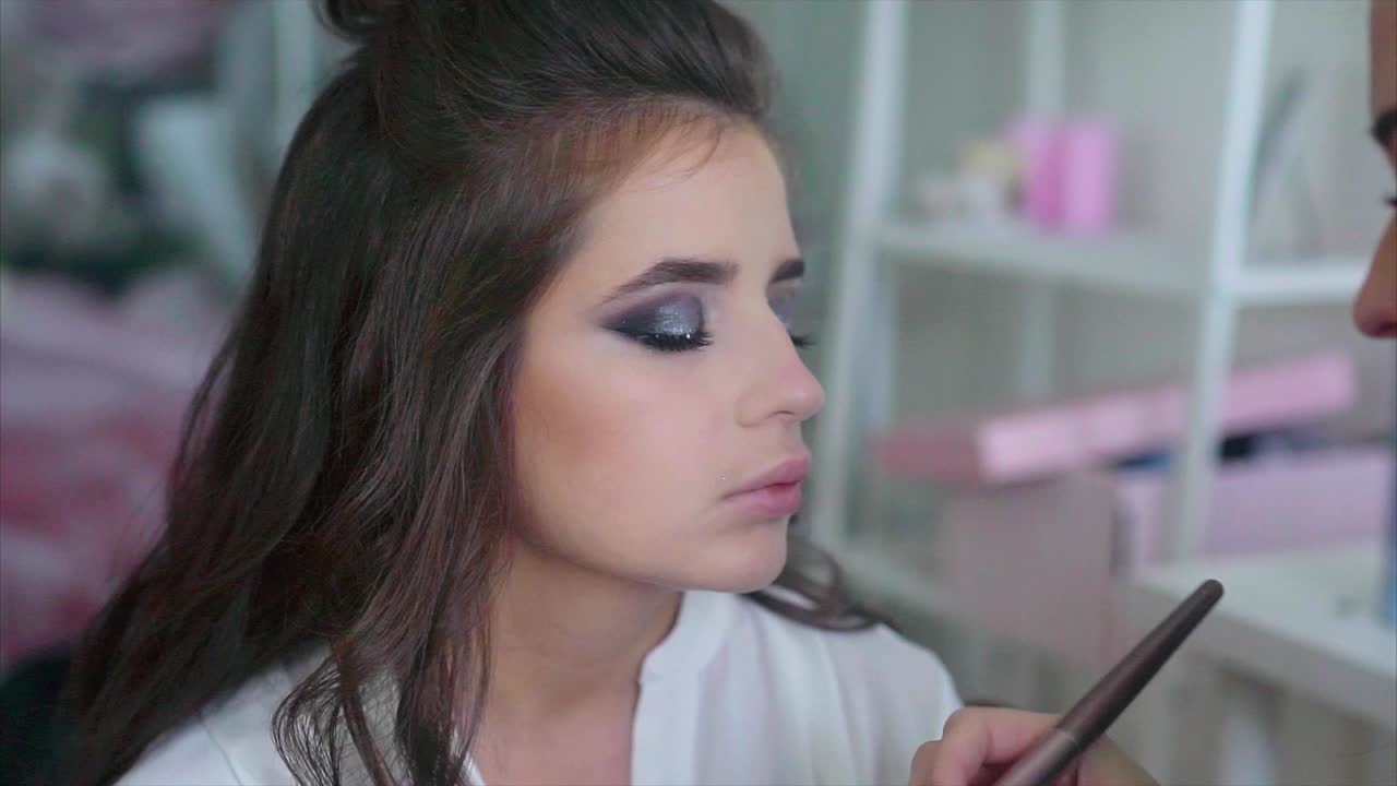 artista de maquillaje aplicando maquillaje a una mujer joven