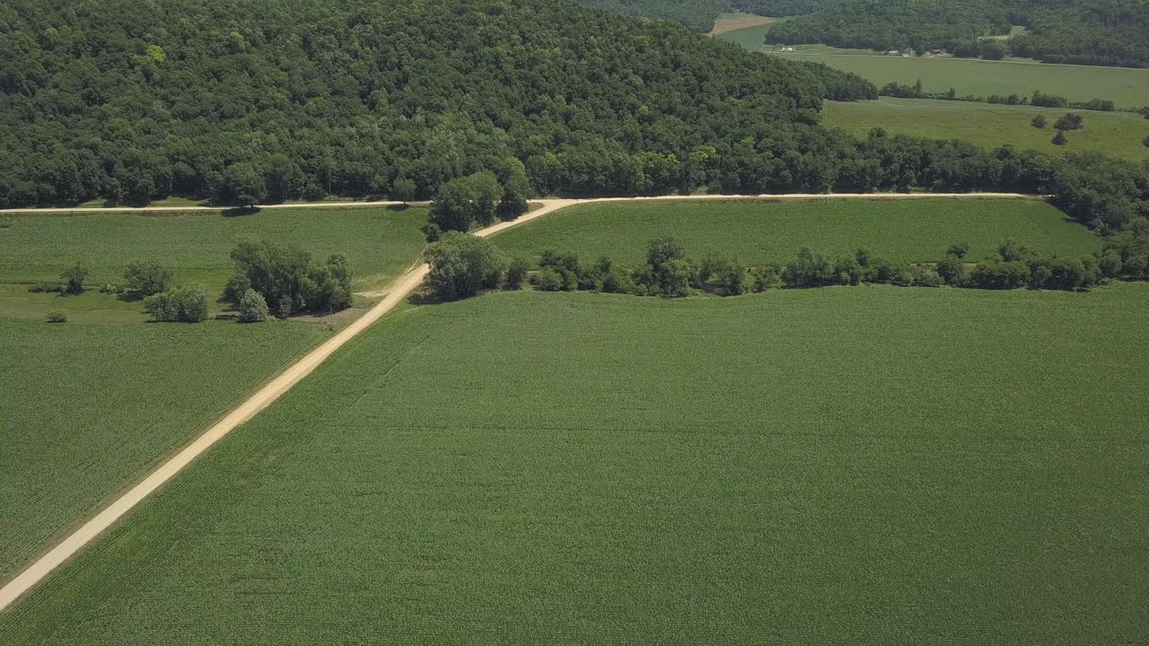 Aerial pull back shot over green Wisconsin landscape and cornfields