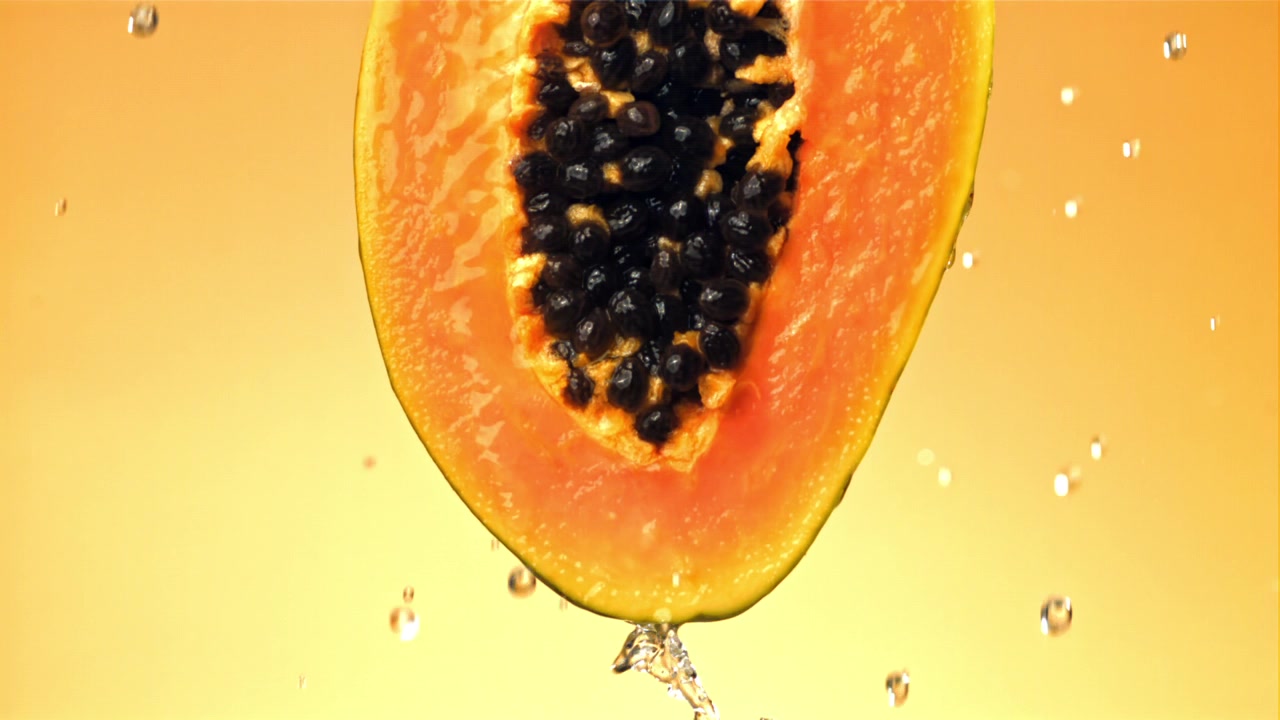 Sakte film: Vann drypper fra en fersk papaya-halvdel.