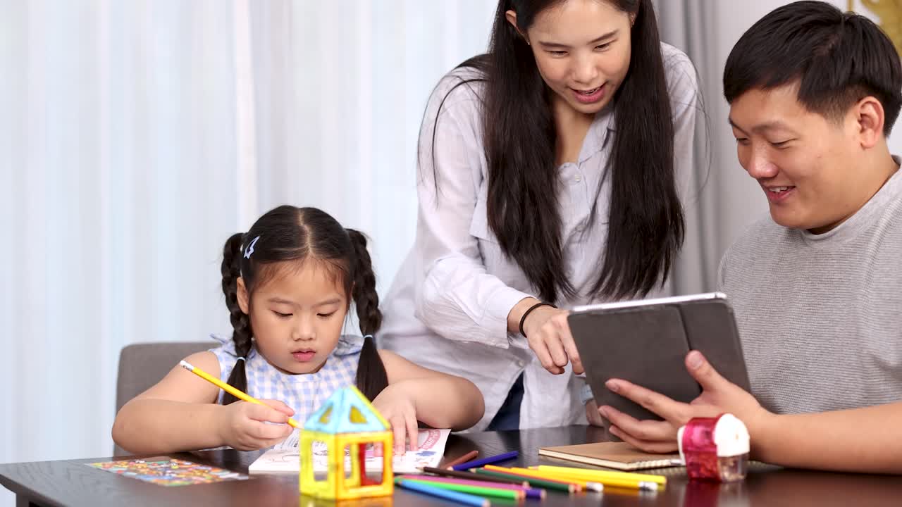 Parents and child engage in playful, educational activities with tablet and art supplies, bright lighting
