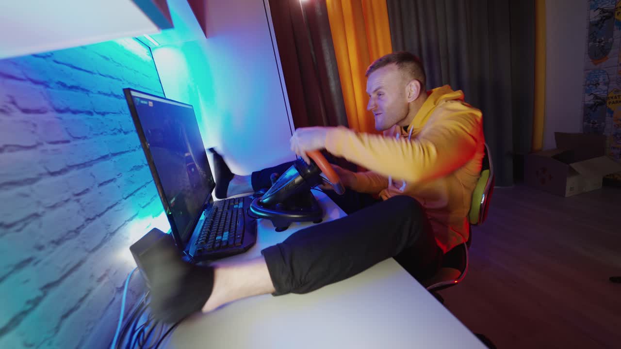 Man playing with steering wheel at home. Young man playing car racing video game at home