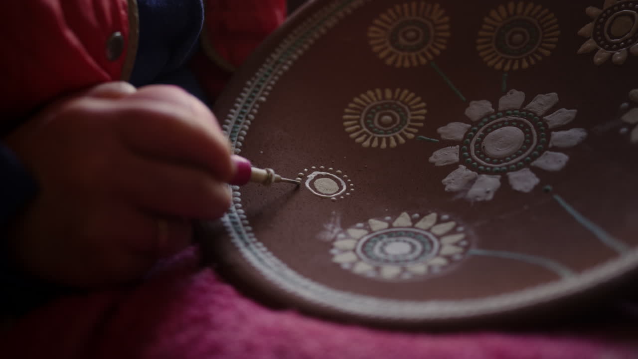 아티스트가 스튜디오에서 점토 판에 장식을 하고 있습니다.