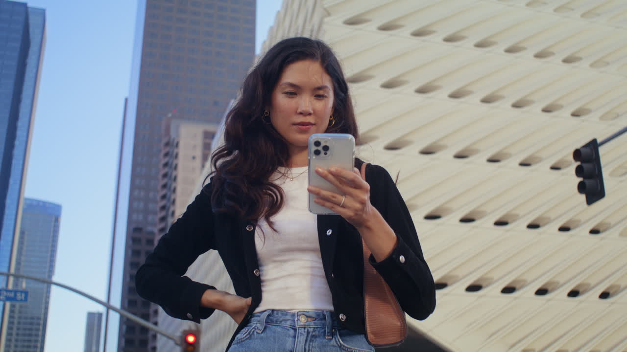 Bella ragazza che usa lo smartphone per strada. Primo piano di una donna asiatica che digita al telefono.