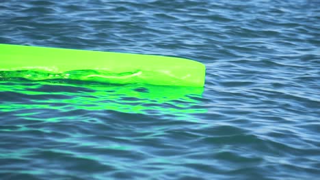 Extreme-close-up-of-the-tip-of-a-pointed-green-canoe-sailing-on-the-water