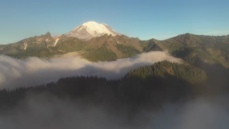 flying through clouds and revealing snow capped mountain summit on sunny summer day