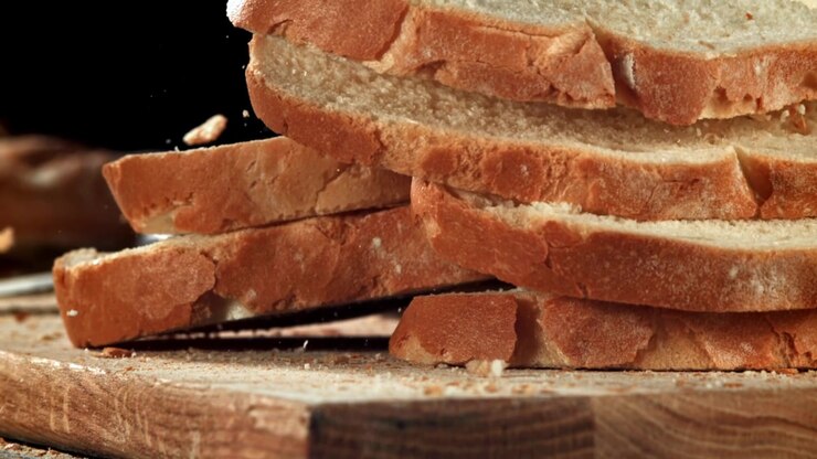 Freshly Baked Bread Slices Falling on a Wooden Board