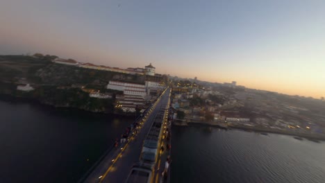 Metro-train-crossing-the-Douro-River-over-Dom-Luis-I-Bridge,-Porto,-Portugal,-authentic-FPV-drone-shot