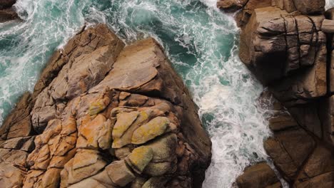 aerial view of ocean waves crashing against rocky cliffs