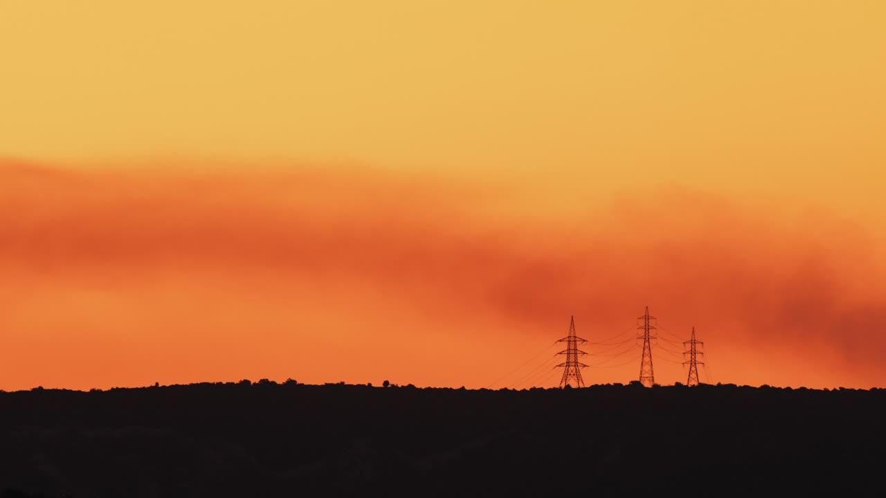 전기 탑 위에 연기가 자욱한 안개 낀 황금빛 새벽