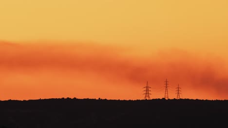 misty golden dawn with smoke over electrical towers