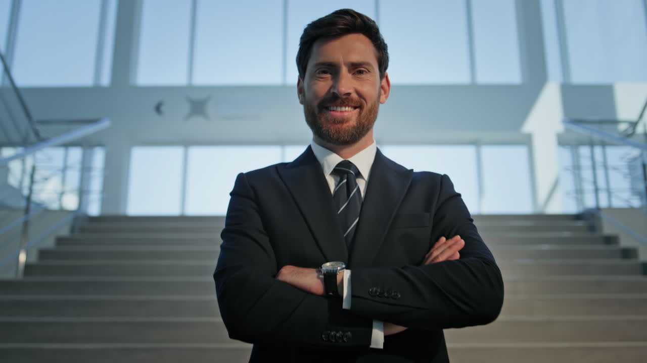 Focused businessman adjusting suit on indoors staircase. Confident executive