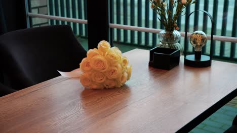 elegant bouquet of cream roses on modern wooden table near window, stylish interior decor with flowers and lamp