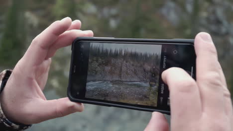 person taking picture of a river and mountains