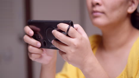 clutching a digital mobile phone with both hands as the woman is playing and browsing some games and the social media on the internet