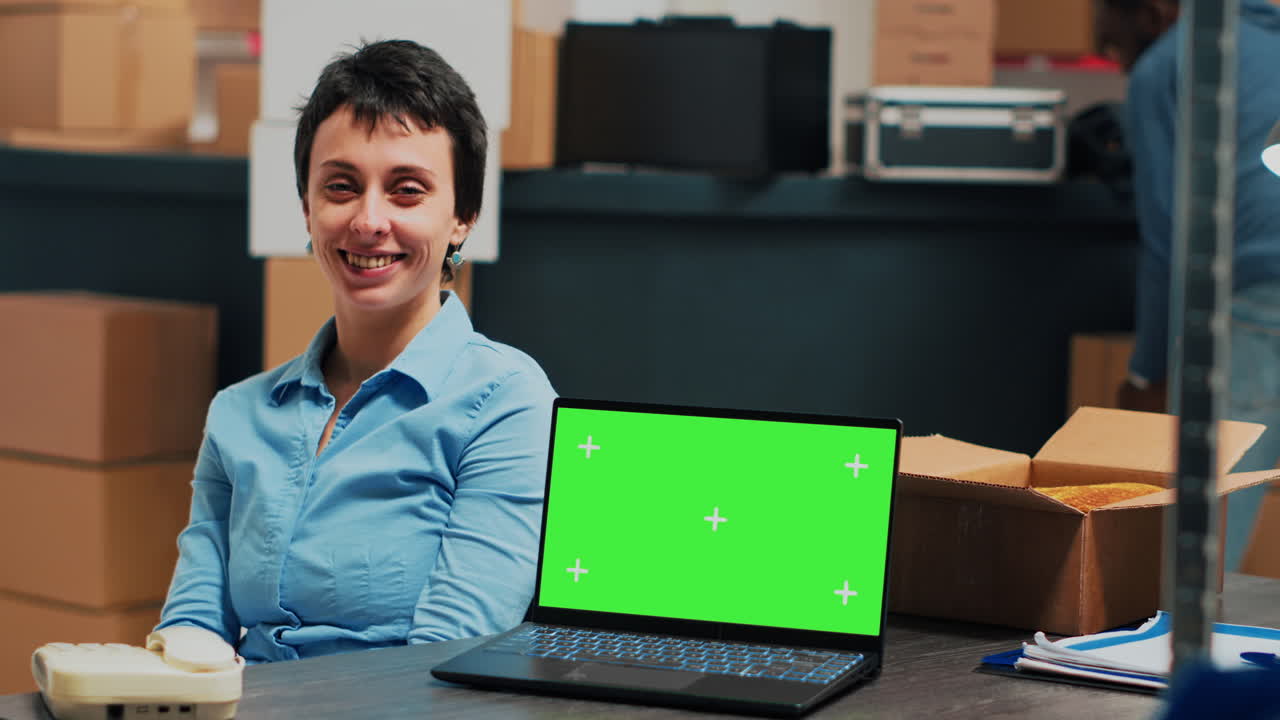 Woman working in warehouse with laptop and phone