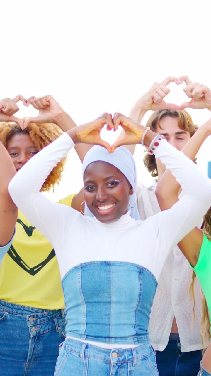 Multi-ethnic friends gesturing a heart shape with hands outdoors