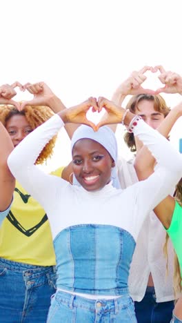 multi-ethnic friends gesturing a heart shape with hands outdoors