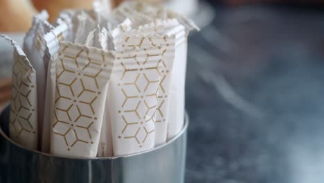 close-up of sugar sachets in a silver dispenser