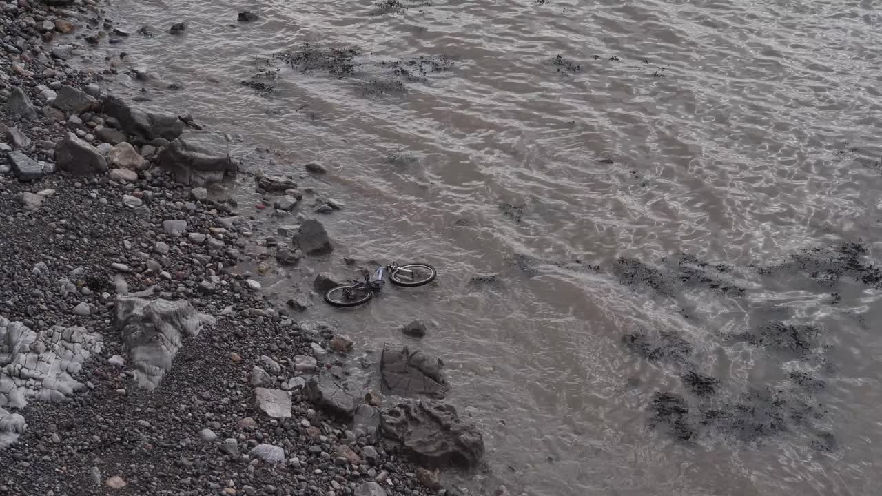 cerca de una bicicleta abandonada en la playa, las olas aplastando una bicicleta que fue arrojada al mar