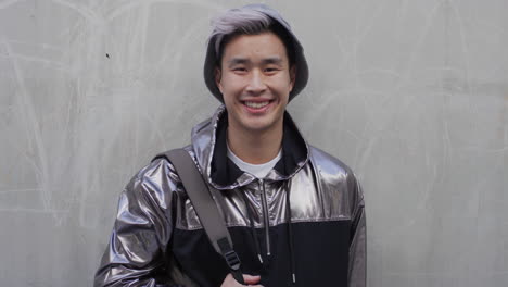 portrait happy young asian man student smiling enjoying relaxed urban lifestyle wearing stylish silver jacket real people series