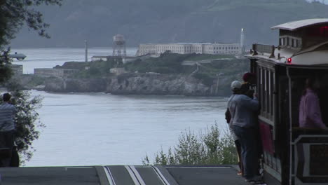 passengers get off a trolley car on a street overlooking alcatraz