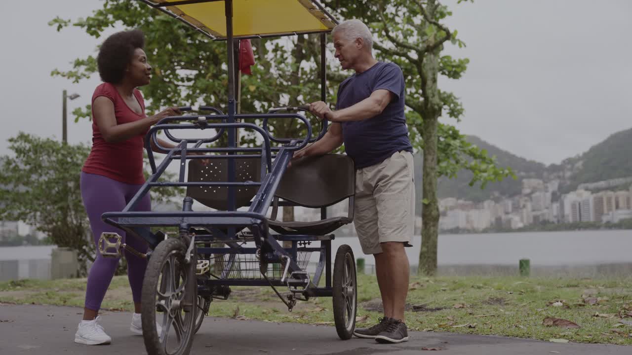 Man and woman talking next to a pedal bike by the lake