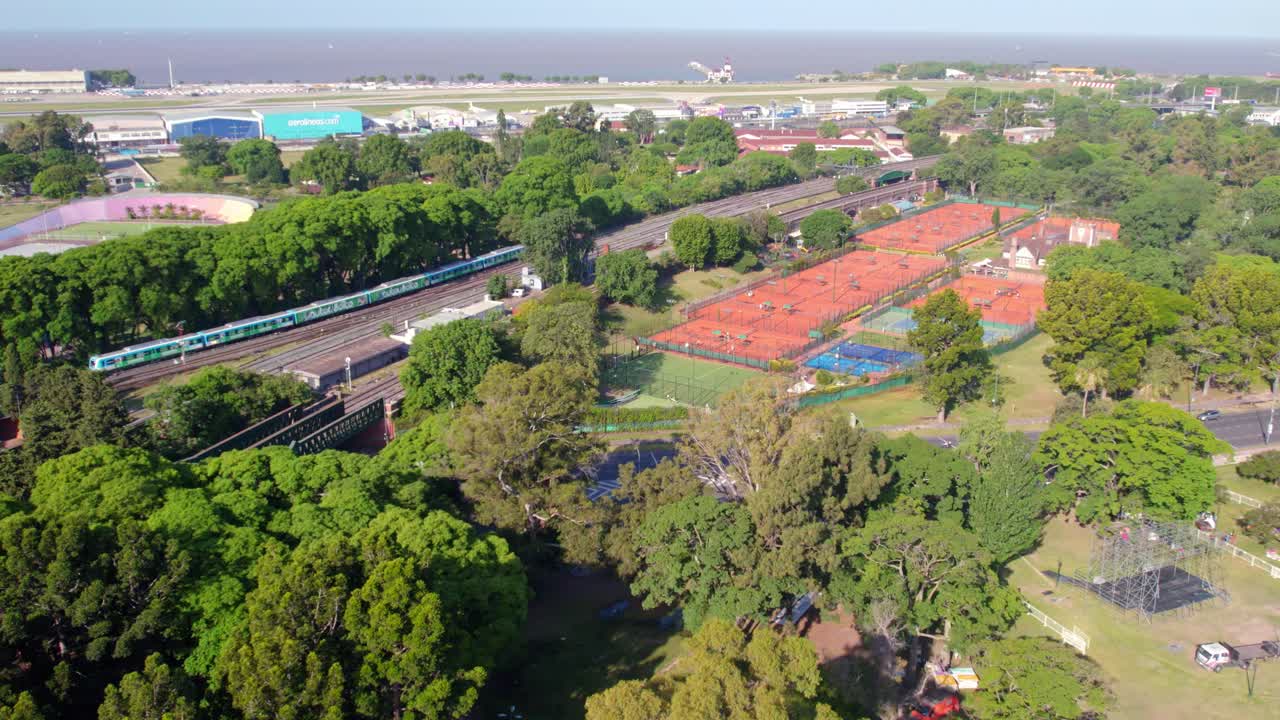 vista aérea de las canchas de tenis de tierra batida y el tren de transporte en movimiento en buenos aires, argentina
