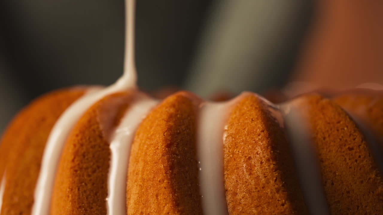White Glaze Being Poured Over Golden-brown Bundt Cake - Easter Food. closeup shot