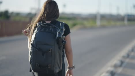 woman walking on a road with a backpack