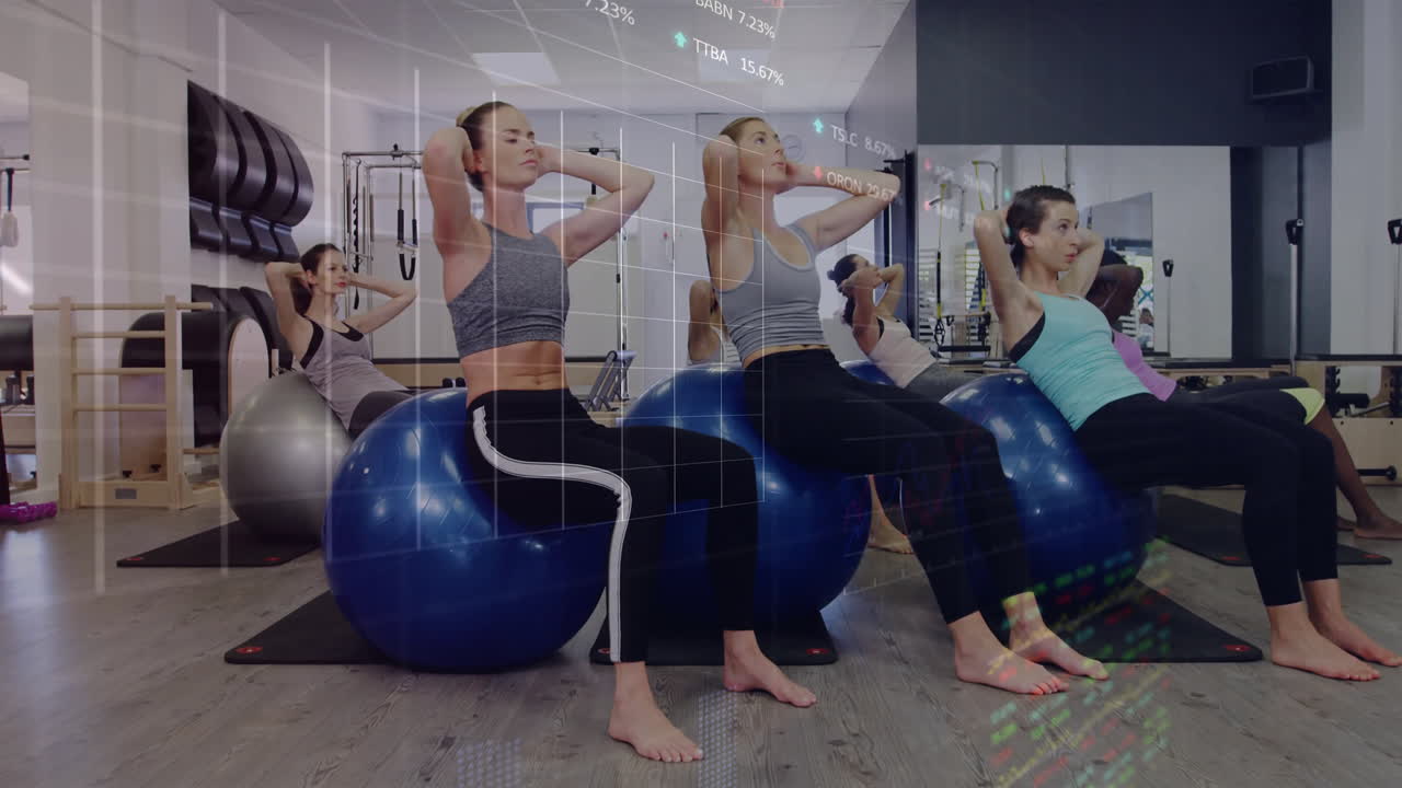Six women performing crunches on stability balls in fitness studio, with animated heart-rate graph