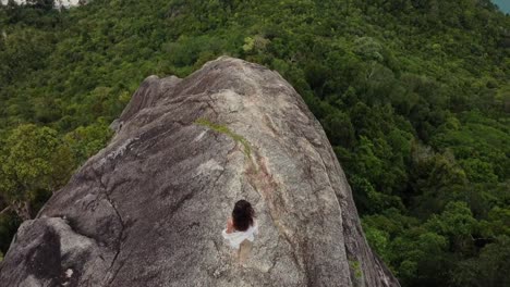 Una-Mujer-Joven-Se-Equilibra-En-La-Cima-De-Un-Gran-Acantilado-Y-Mira-Hacia-La-Jungla,-Una-Vista-Superior-Real