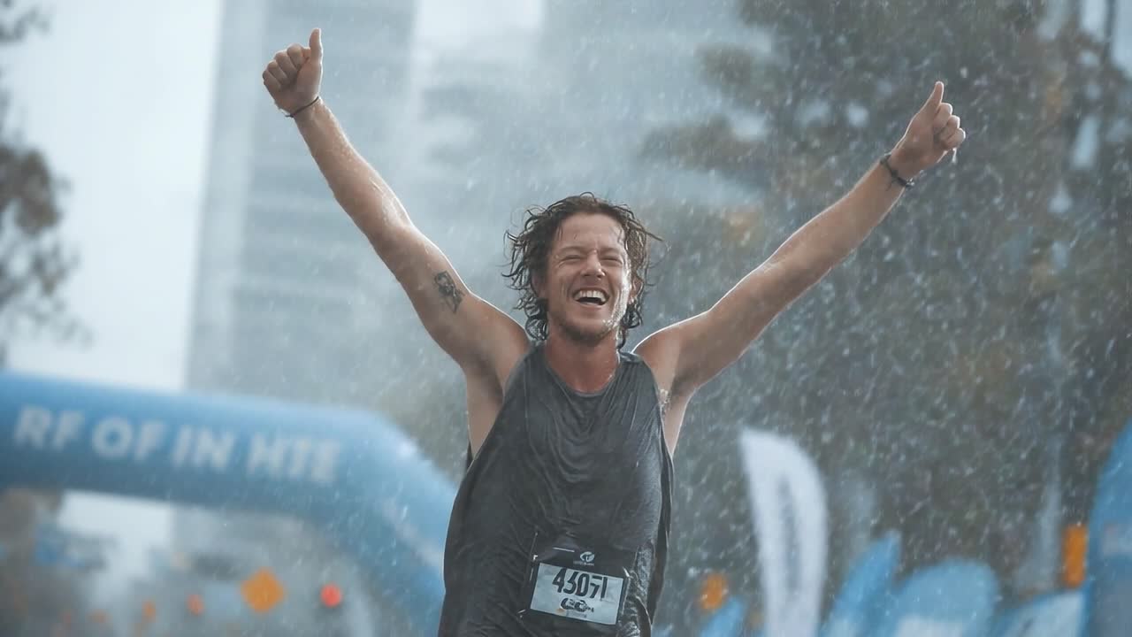 A Joyful Runner Celebrating Victory in the Rain with Outstretched Arms, Embracing the Challenge and Thrill of Completing the Race Under Drizzling Skies