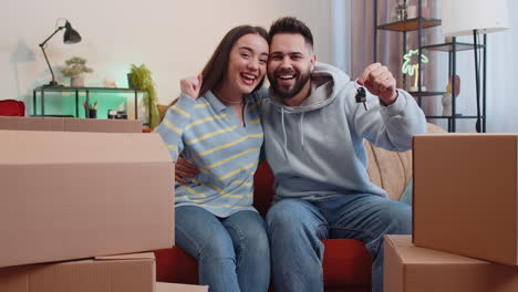 family couple showing the keys of new home house apartment buying or renting real estate property