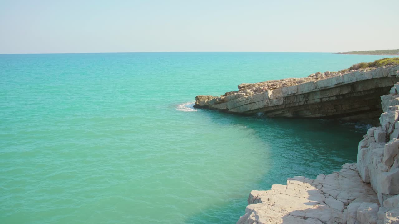 Onde marine che si infrangono sulla costa rocciosa e grotta in una giornata estiva