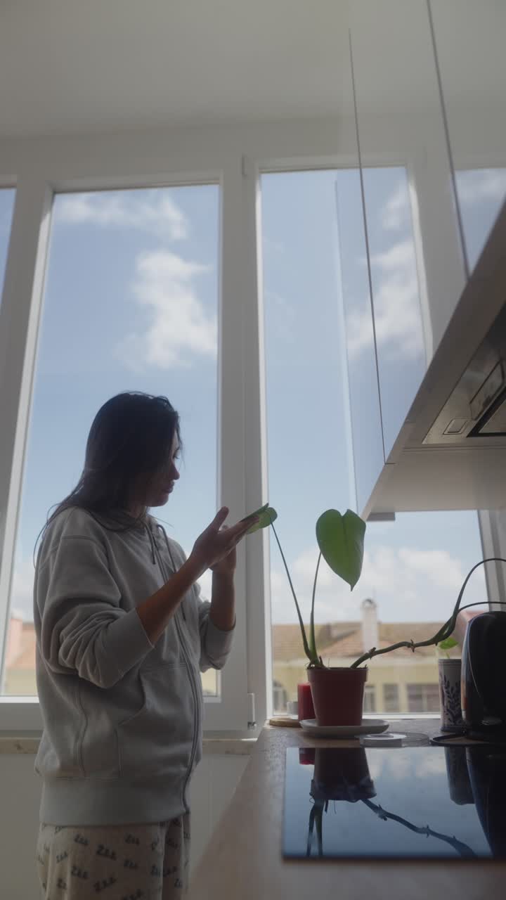 Woman Taking Care of Houseplant in Kitchen