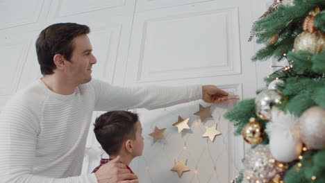 smiling father decorating living room with son together.