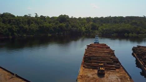 deforestation: loading and stacking logs from the amazon rainforest onto barges for transport - aerial flyover