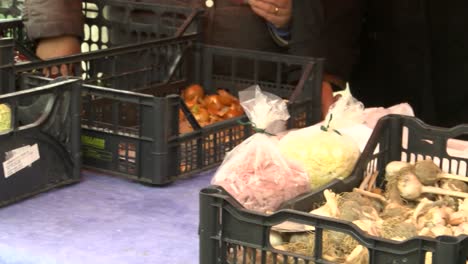 farmer-selling-vegetables-in-market,-pan-shot-of-home-grown-products-in-black-plastic-crates