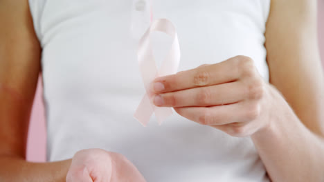 Mid-section-of-woman-holding-breast-cancer-awareness-ribbon