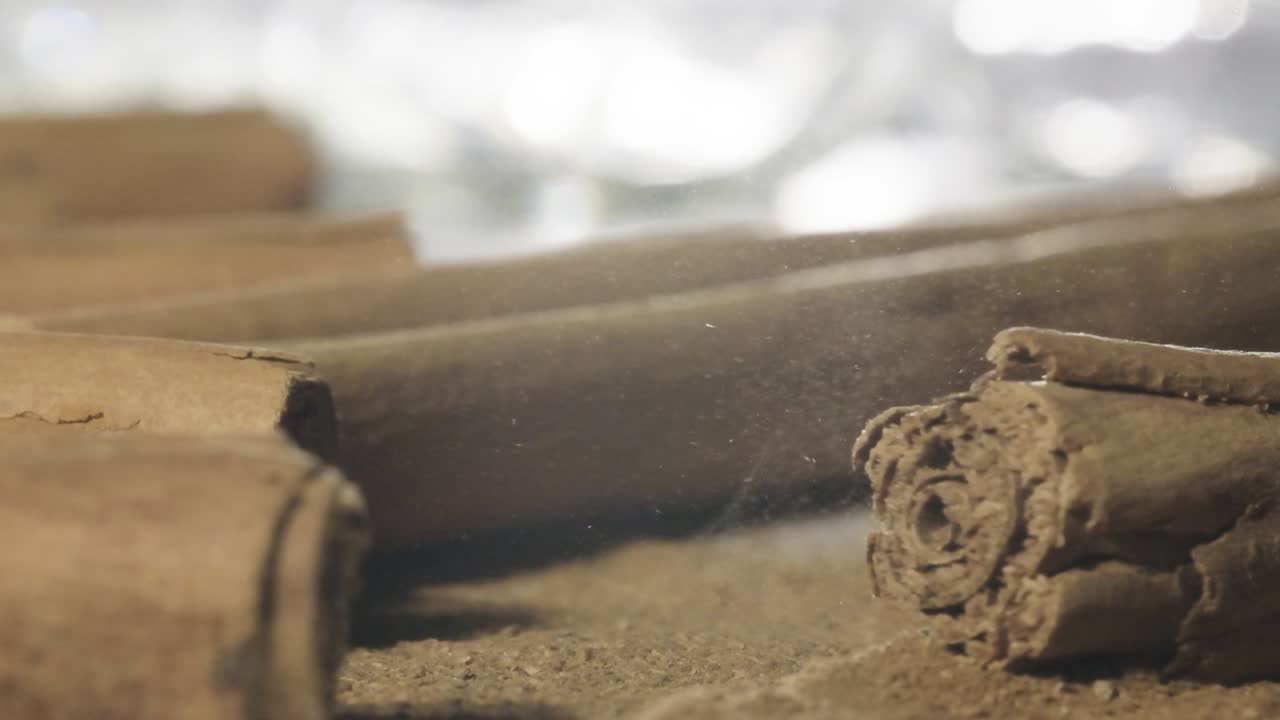Makrobilde av kanelstang som lander oppå kanelpulver, sakte film