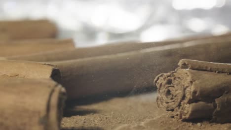 Macro-shot-of-Cinnamon-stick-landing-on-top-of-Cinnamon-powder,-Slow-motion