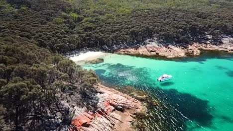 Boat-Anchored-in-a-small-secret-Cove-filmed-with-a-Drone,-Hazard-beach-Wineglass-bay-Tasmania