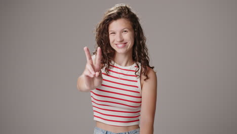 Studio-portrait-shot-of-happy-young-brunette-woman-making-peace-sign